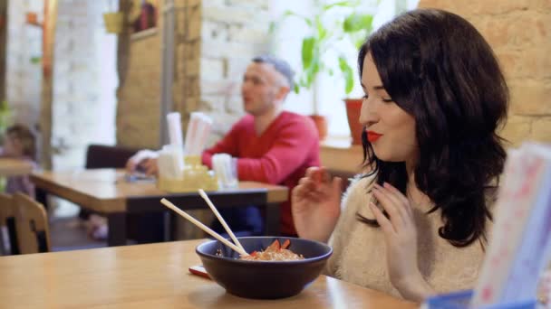 Bautiful kvinna försöker en välsmakande traditionell maträtt i koreansk restaurang — Stockvideo