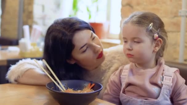 Jovem mulher pede a sua filhinha para experimentar um macarrão coreano delicioso — Vídeo de Stock