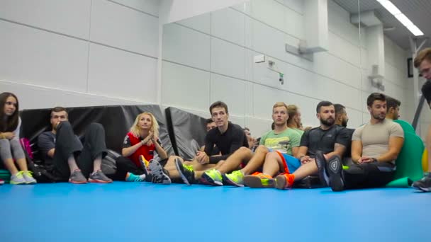 Team av unga människor sitter på golvet i gymmet på utbildningen — Stockvideo