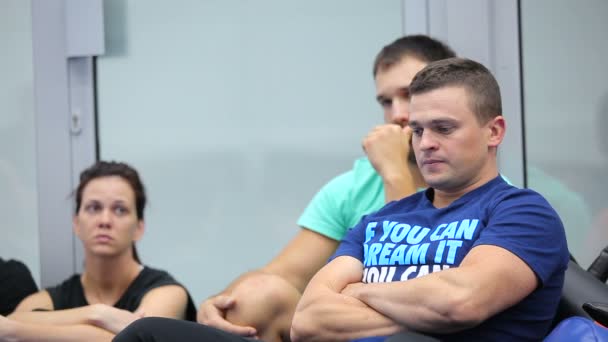 Dos hombres y una mujer sentados en el gimnasio en el entrenamiento — Vídeo de stock