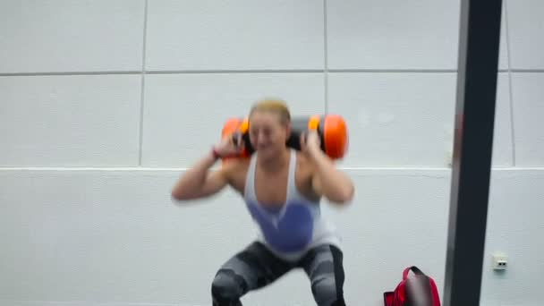 Sportlerin hockt mit Gewichten im Fitnessstudio — Stockvideo