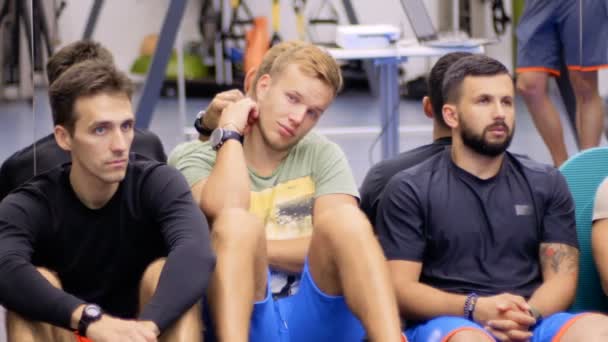 Equipe de jovens desportistas escuta seminário treinador no ginásio — Vídeo de Stock