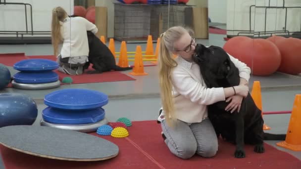 Cynologist rilassarsi dopo l'allenamento seduto sul pavimento e abbracciare il cane — Video Stock