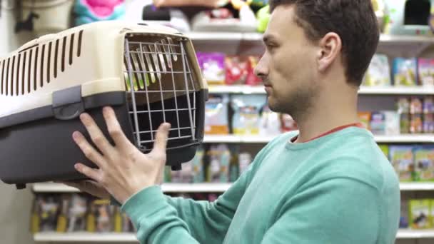 Hombre elegir caja para el transporte de su gato en la tienda de mascotas — Vídeo de stock