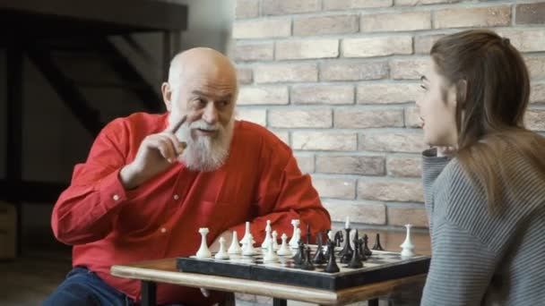 Grand-père enseigne à sa petite-fille à construire une stratégie pendant le jeu d'échecs — Video