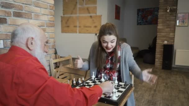 젊은 여 자가 할아버지와 체스를 재생 — 비디오