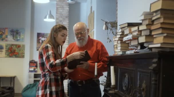 Gray-haired grandfather and granddaughter read interesting book together — Stock Video