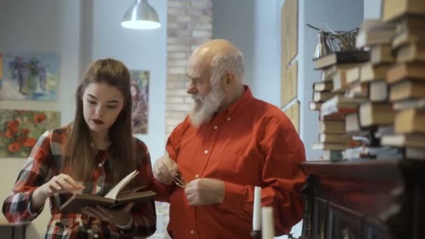 Mladá dívka číst zajímavou knihu s její děda — Stock video