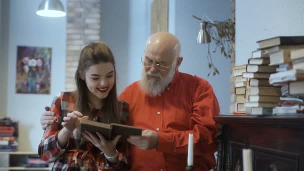 Homem sênior lê livro junto com sua adorável neta — Vídeo de Stock