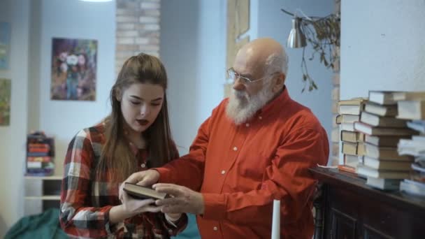 Abuelo y nieta discute libro de pie cerca del piano — Vídeos de Stock