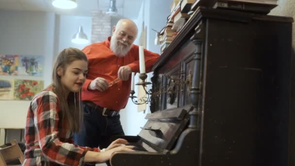 Красивая девушка играет на пианино для своего дедушки — стоковое видео