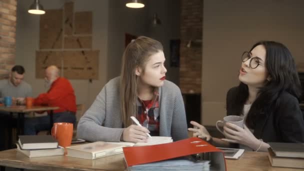 Twee jonge meisjes hebben een pauze tijdens de voorbereiding op de examens van de Universiteit en praten — Stockvideo