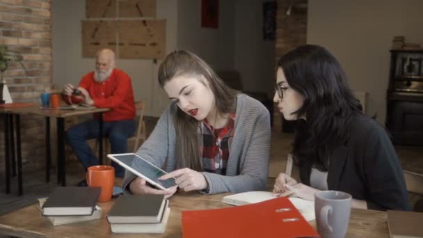 Δύο νεαρά κορίτσια συνομιλίες σχετικά με θέματα εργασίας χρησιμοποιώντας ψηφιακό tablet — Αρχείο Βίντεο