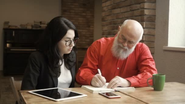 Volwassen man schrijft in notitieblok — Stockvideo