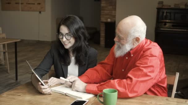 Ung kvinna med mogen man ser på skärmen av digitala tablett och berättar om det — Stockvideo