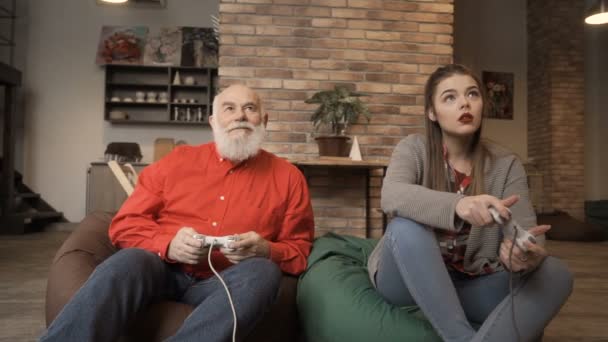 Старший мужчина играет в видеоигры с молодой девушкой — стоковое видео