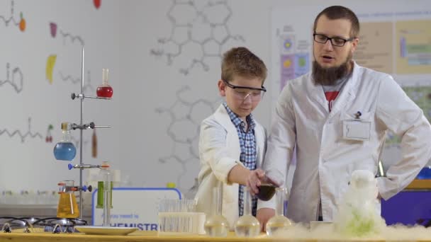 Laboratorium assistent maakt chemische experimenten met kleurrijke vloeistoffen met leerling — Stockvideo