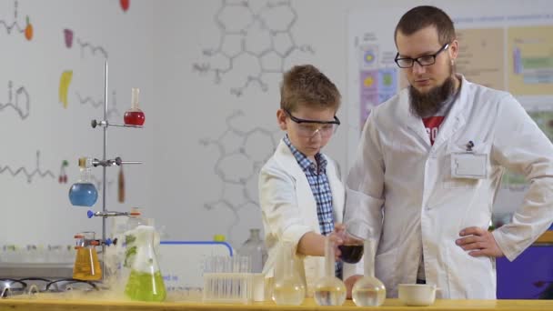 Pequeño científico hace experimento químico en laboratorio con asistente — Vídeos de Stock