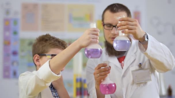Химик и ученик проводят эксперименты с сухим льдом и цветными жидкостями — стоковое видео