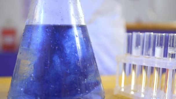 Cientista colocar gelo seco em um líquido azul — Vídeo de Stock