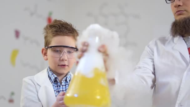 Os cientistas olham para o líquido amarelo fumegante — Vídeo de Stock