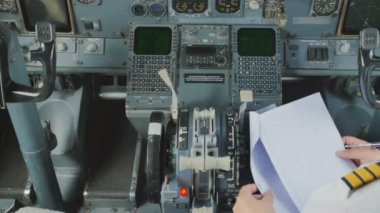 Pilot kabininde oturuyor ve uçuş önce belgeleri denetler