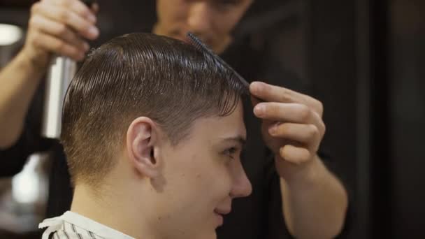 Profissional estilista pentes mans cabelo e polvilhe-lo com água — Vídeo de Stock