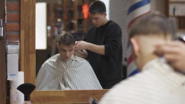 Barbiere professionista taglia i capelli con rasoio elettrico a un ragazzo giovane — Video Stock