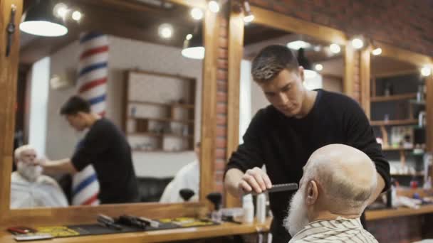 Stylist combs gray beard of senior man — Stock Video