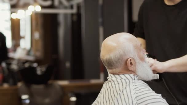 Stylist taglia la barba grigia con rasoio elettrico per l'uomo anziano — Video Stock