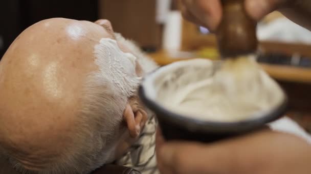 Barber aplica la crema de afeitar a la barba del hombre maduro — Vídeos de Stock