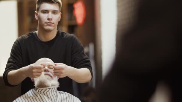 Frisör gör eleganta skägg för mogen man i barbershop — Stockvideo