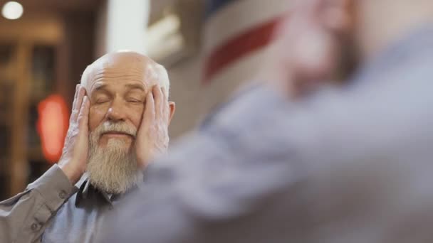 Handsome mature man enjoys himself in barbershop in front of the mirror — Stock Video