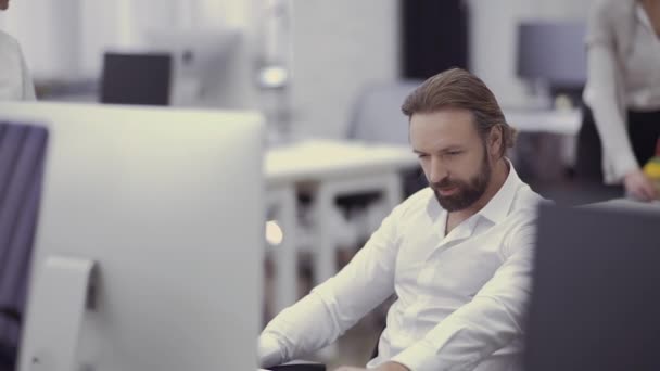 Hombre de negocios guapo trabaja en la computadora en la oficina — Vídeos de Stock