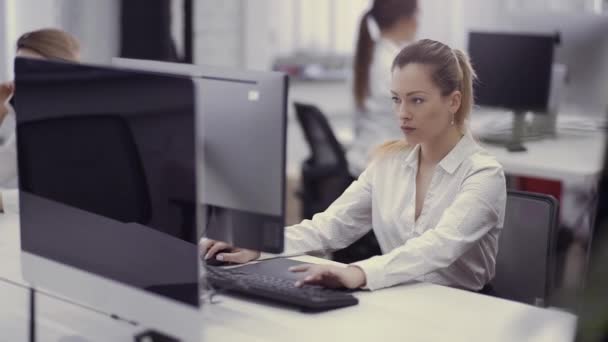 Привлекательная кавказка работает за компьютером в офисе — стоковое видео