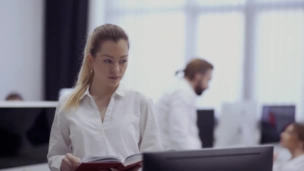 Hermosa mujer de negocios con cuaderno en la oficina — Vídeos de Stock