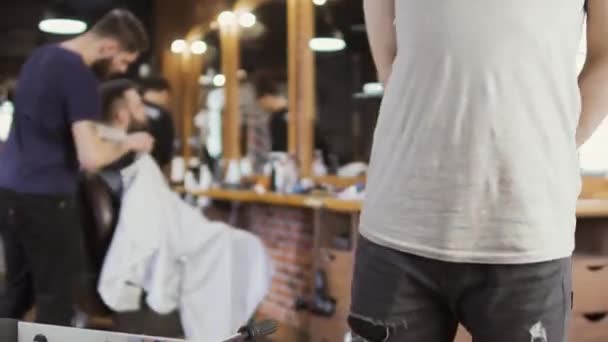 若い男は、理髪店でテーブル サッカーします。 — ストック動画