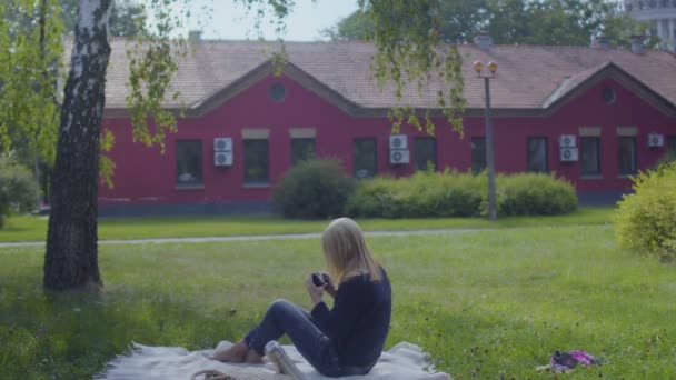Молодая Женщина Отдыхает Одеяле Парке Фотографирует Природу Вокруг Себя Самка — стоковое видео