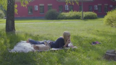 Genç kadın üzerinde rahatlatıcı paket Park'ta ve elma yemek. Temiz hava ve güneşli havalarda yalnız doğa üzerinde eğleniyor dişi sahiptir.