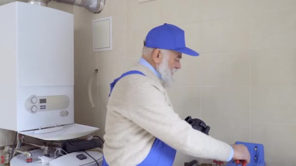 Anciano vistiendo mono azul sostiene parte de plástico de la tubería en las manos — Vídeos de Stock