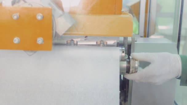 Worker adjusts the paper tape inside the conveyor for making tea bags — Stock Video