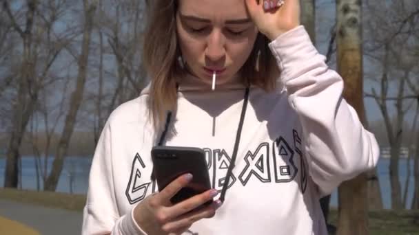 Menina com mensagens pirulito com amigos e fica no parque com skate — Vídeo de Stock