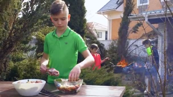 Boy put marinated meat on a skewer — Stock Video