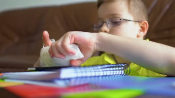 Lindo niño con la mano rota no puede hacer su tarea — Vídeos de Stock