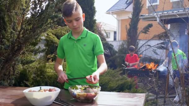 Teenager cook barbecue in the garden, slowmotion — Stock Video