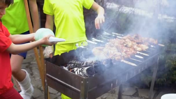 Tři chlapci grilování masa na open air — Stock video