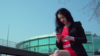 Telefonunuzun ve iş merkezi arka plan Kırmızı elbiseli güzel zarif kadın