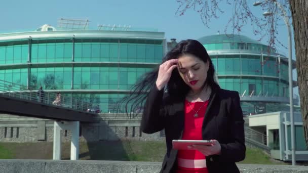 Stylish businesswoman in red dress using digital tablet outdoors — Stock Video