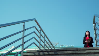 Dijital tablet ellerde ile şık esmer merdivenlere köprünün üzerinde yürür.