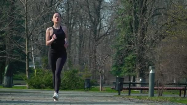Спортсменка біжить у весняному парку — стокове відео